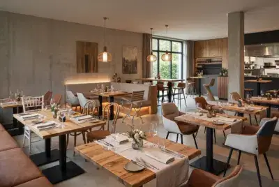 Stilvolle Restaurant Einrichtung mit verschiedenen Gastromöbeln wie massiven Holztischen, bequemen Polsterstühlen und modernen Stehtischen für ein ansprechendes Ambiente.