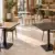 Restauranttische und Cafétische mit quadratischen und runden Tischplatten in Holzoptik, Weiß und schwarzer Marmoroptik in einem modernen Restaurant.